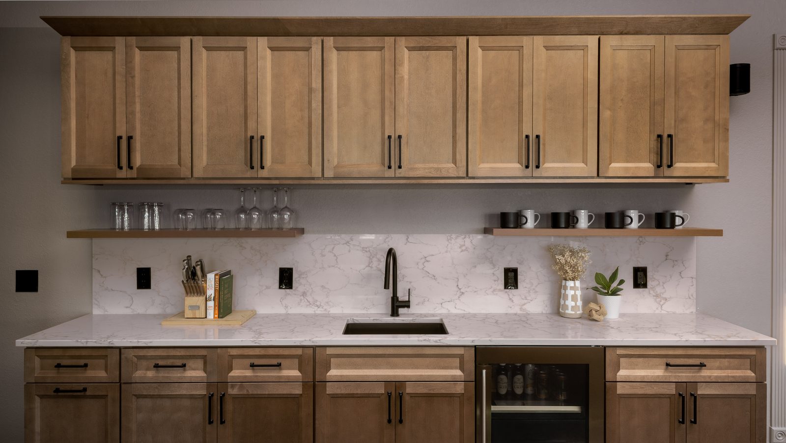 Built-in beverage bar with maple cabinetry, floating shelves, a marble backsplash, and an under-counter wine refrigerator.