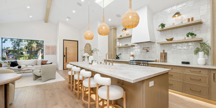 A stunning, high-end open-concept kitchen with a large island, quartz countertops, woven pendant lights, and a seamless flow into a modern living area.